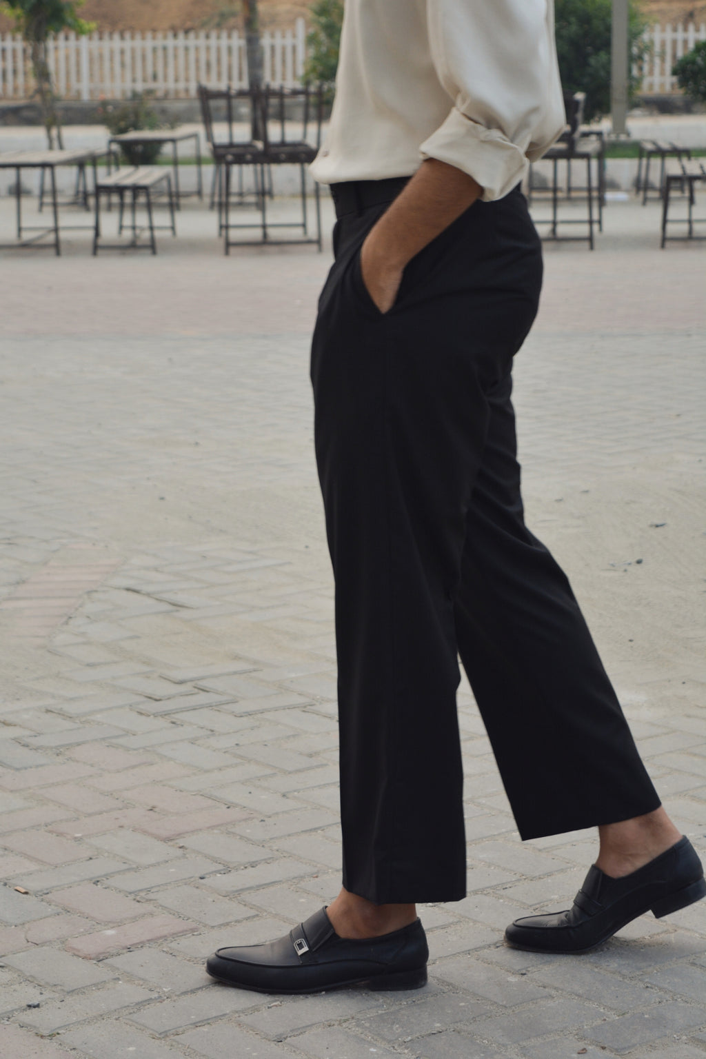 Side angle of black loose pleated pants highlighting generous wide fit