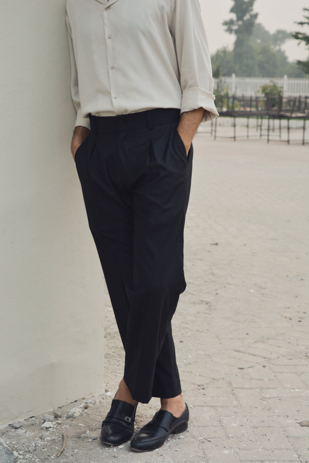 Black loose pleated pants for men with relaxed silhouette and front pleats