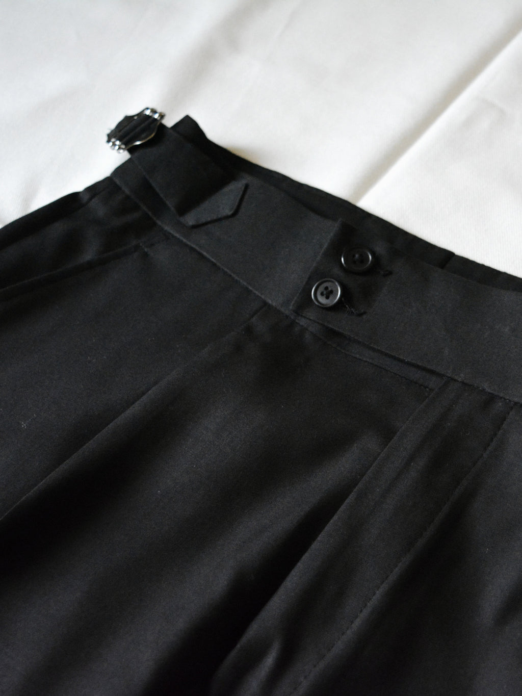 Front view of black pleated adjustable pants for men with tailored fit and clean silhouette