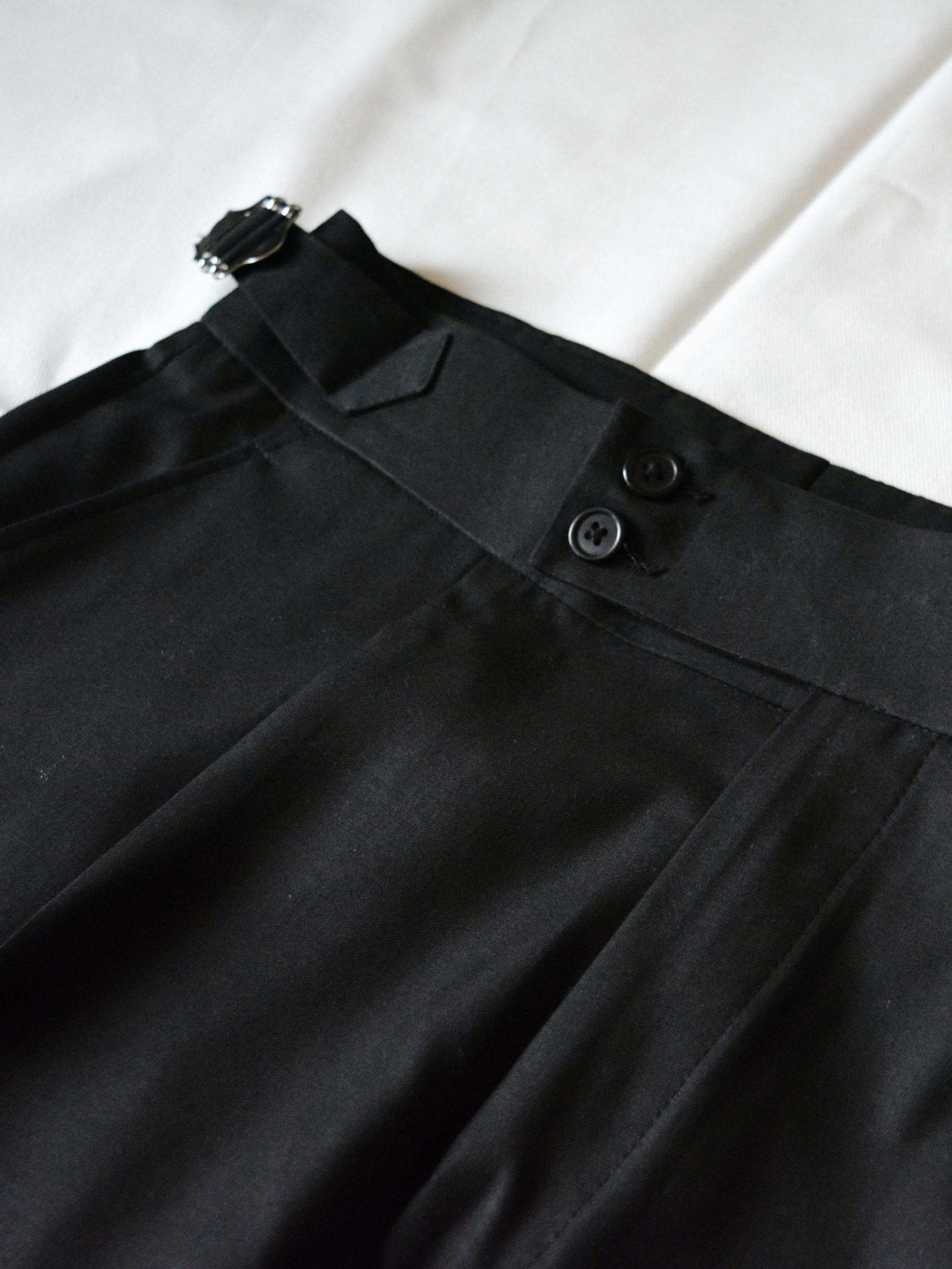 Front view of black pleated adjustable pants for men with tailored fit and clean silhouette