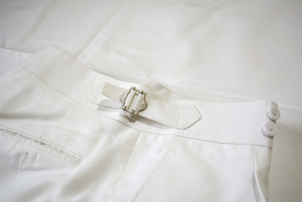 Men’s off-white tailored pleated trousers with adjustable side buckles and double waist button closure
